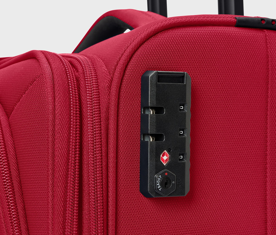 Detail červeného kufra s číselným zámkom.