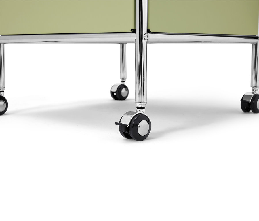 Detailný záber svetlozeleného pojazdného regálu s chrómovanými nohami na bielom pozadí.