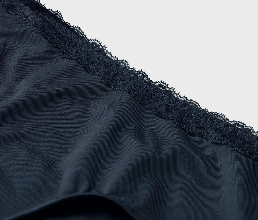Detailný záber na tmavomodrú spodnú bielizeň s čipkovaným lemom.