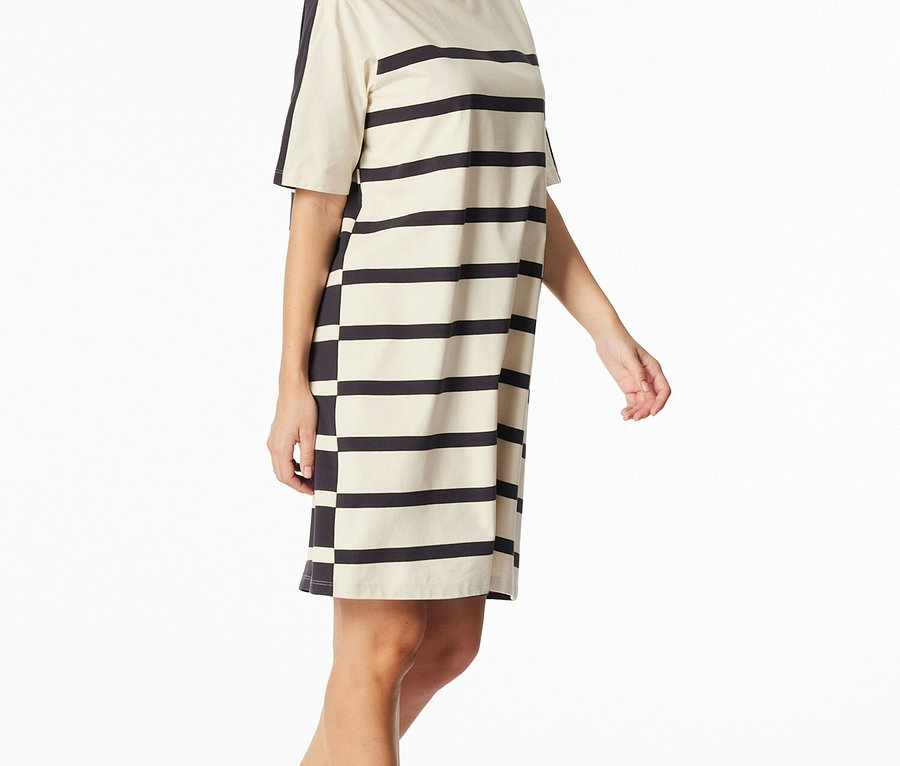 Žena má na sebe pruhované tričkové šaty s krátkym rukávom v čiernej a krémovej farbe.
