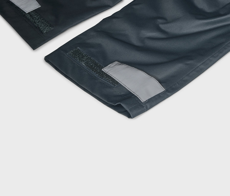 Detailný pohľad na tmavomodré nohavice so suchým zipsom a reflexnými detailmi na lemoch.