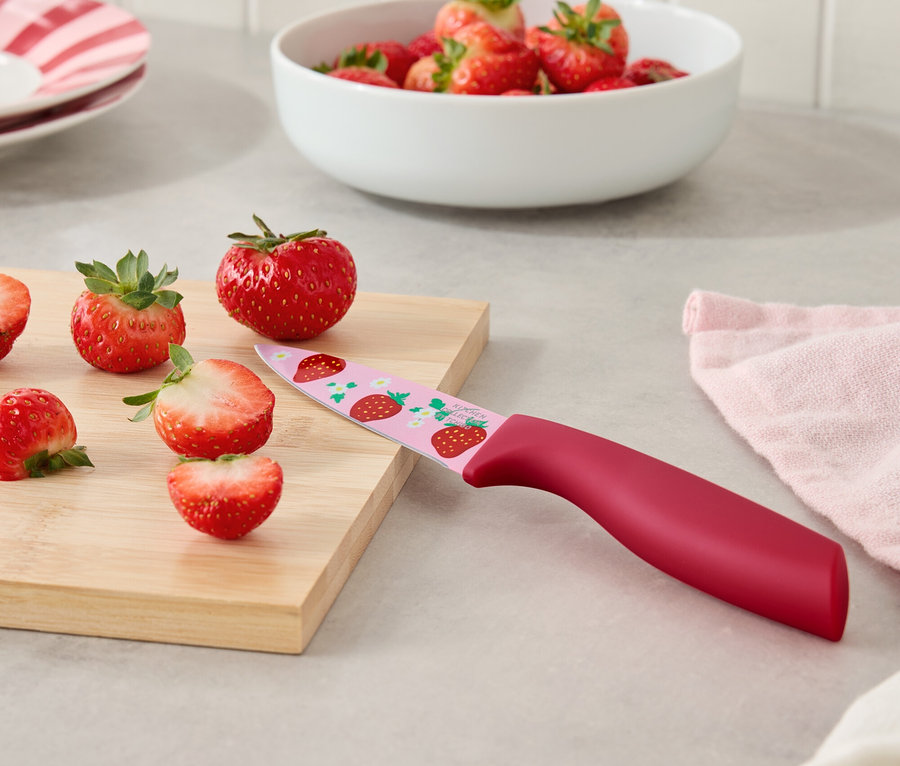 Jahody a nôž s jahodovým vzorom na doske na krájanie.