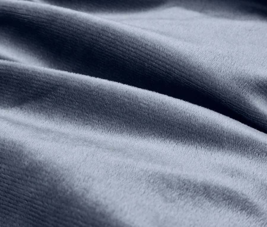 Detail modro-sivej, mäkkej, zamatovej látky s jemnými záhybmi.
