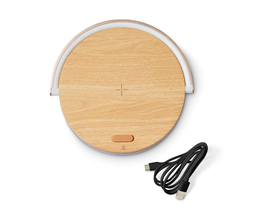Oválny Bluetooth reproduktor s bezdrôtovou nabíjačkou a LED nočným svetlom na bielom pozadí, vedľa neho je čierny nabíjací kábel.