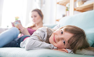 Pohodlie vďaka dobrej kvalite: Smejúce sa dieťa leží na sedačke, zatiaľ čo mama číta knihu.