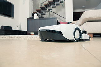 Elektrický pomocník: robotický vysávač jazdí po dláždenej podlahe v obývacej izbe.